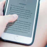 Close-up of a hand holding a smartphone displaying the Bible book Genesis on screen.