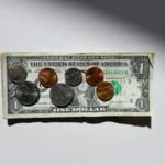 One-dollar bill with a mix of pennies, nickels, and dimes laid on top on a white surface
